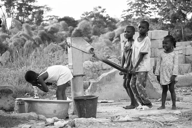A group of children collecting water at a pipe well
